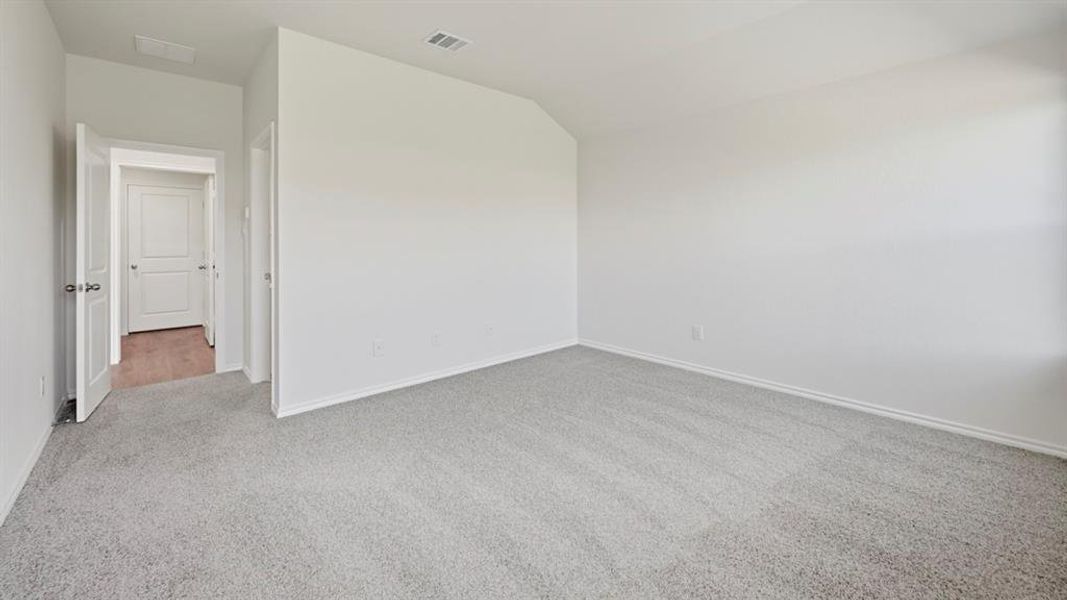 Unfurnished room featuring light colored carpet and lofted ceiling