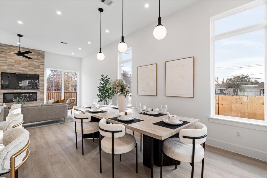 Generous glass and elevated ceilings give this dining space an airy presence, seamlessly extending toward the living room and fireplace beyond. Refined finishes and soft textures create warmth without excess.