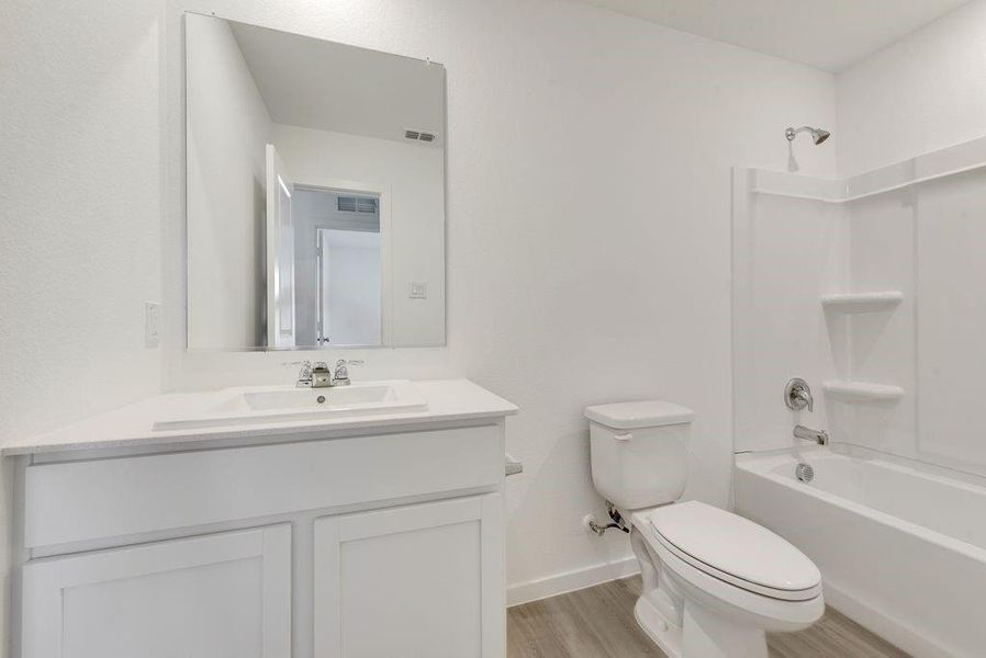 Full bathroom with vanity, hardwood / wood-style flooring, shower / bathtub combination, and toilet