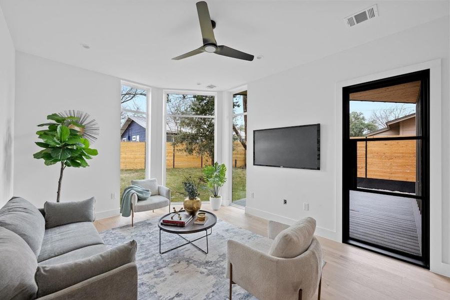 Living room with wood finished floors, ceiling fan, and floor to ceiling windows