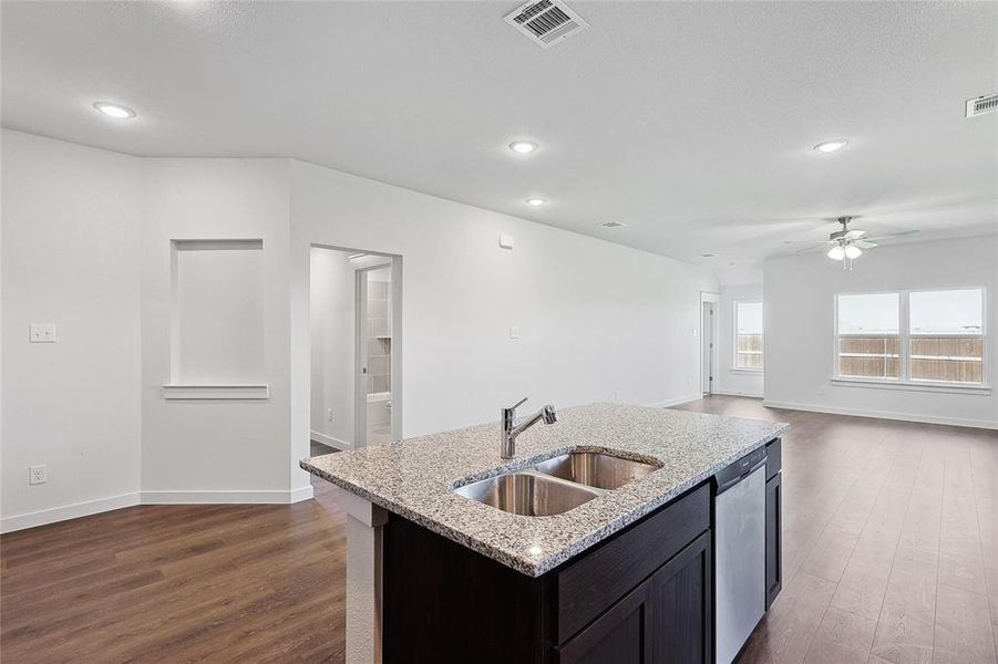 Kitchen featuring a kitchen island with sink, dishwasher, sink, ceiling fan, and dark wood-type flooring