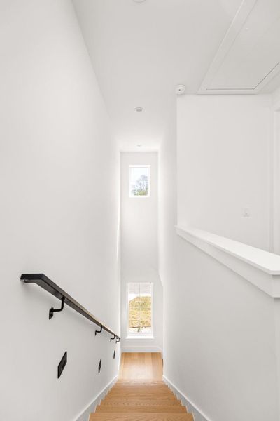 Stairway featuring a high ceiling and wood finished floors