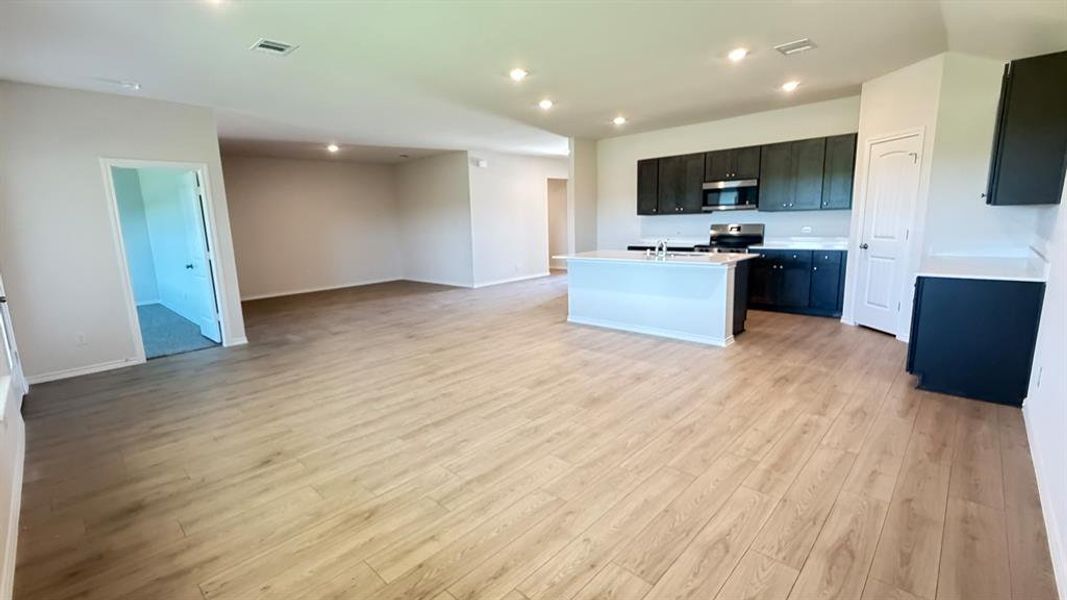 Open-concept living space with wood-finish flooring, recessed lighting, and a modern kitchen