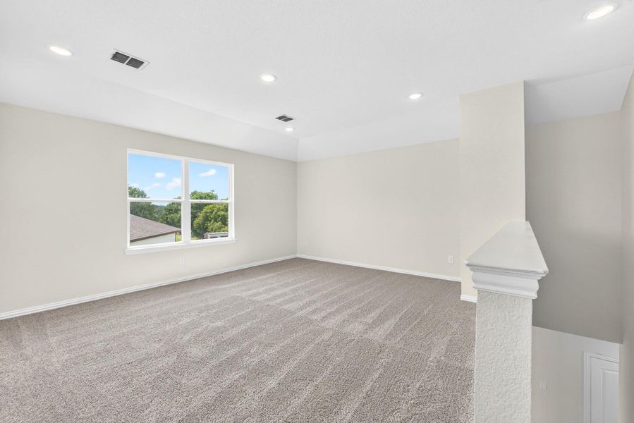 A spacious upper-level loft features wall-to-wall carpeting and recessed lighting.