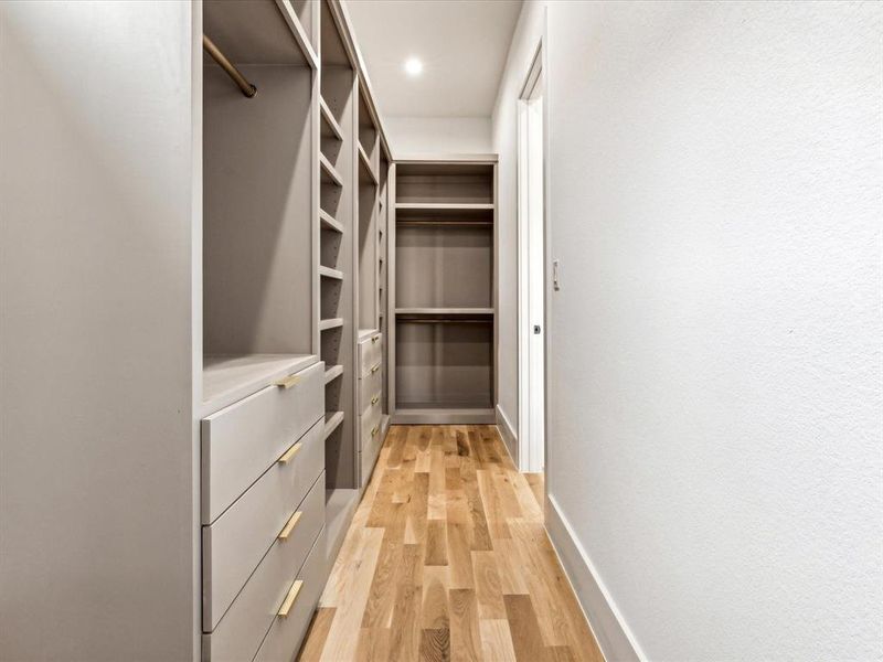 Walk in closet with light hardwood / wood-style flooring