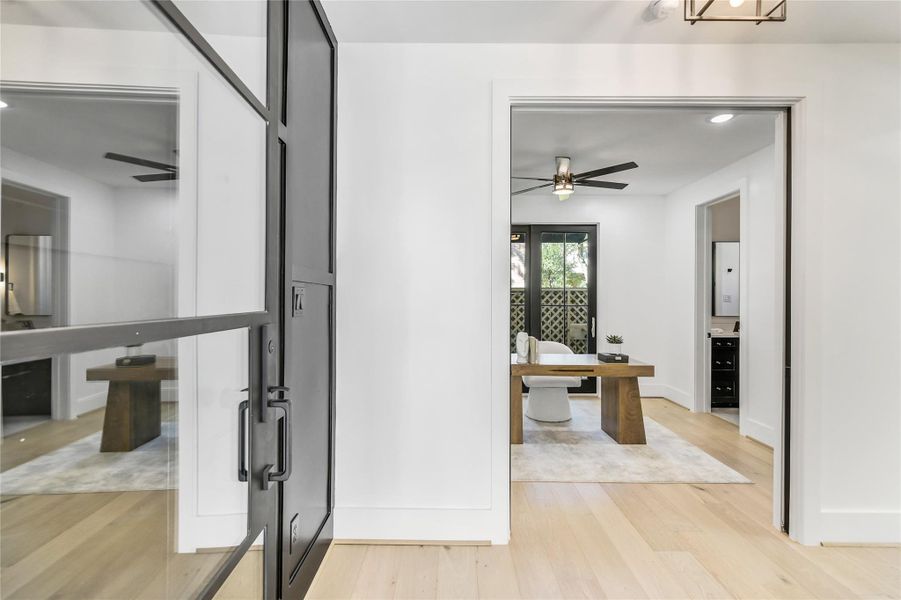 Grand entry with sleek glass and iron door, wide-plank wood flooring, and a view into the private first-floor office—offering a sophisticated first impression. Grand entry with sleek glass and iron door, wide-plank wood flooring, and a view into the private first-floor office—offering a sophisticated first impression.