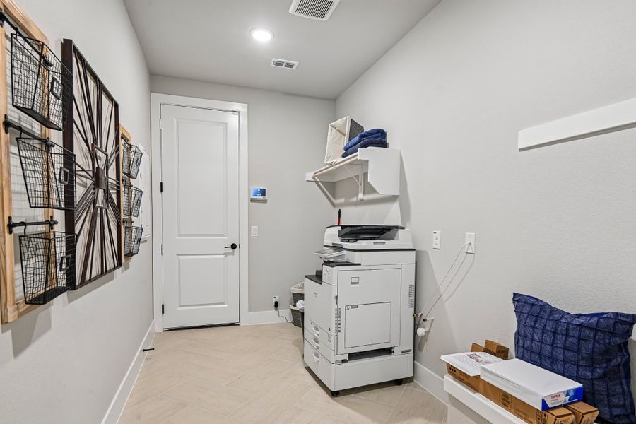 Utility room with large printer, wall-mounted wire baskets, and tile floors