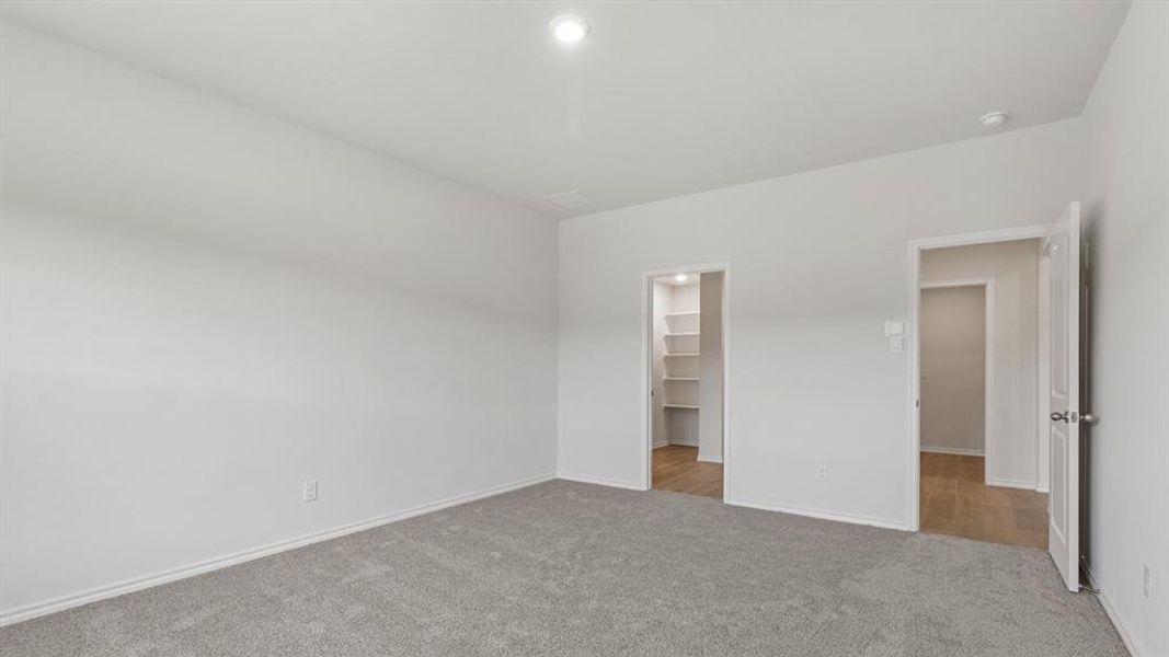 Spacious room featuring light gray carpeting, white walls, and a recessed ceiling light fixture