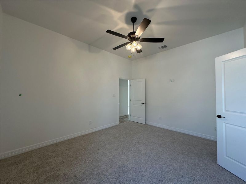 Carpeted spare room featuring baseboards and ceiling fan