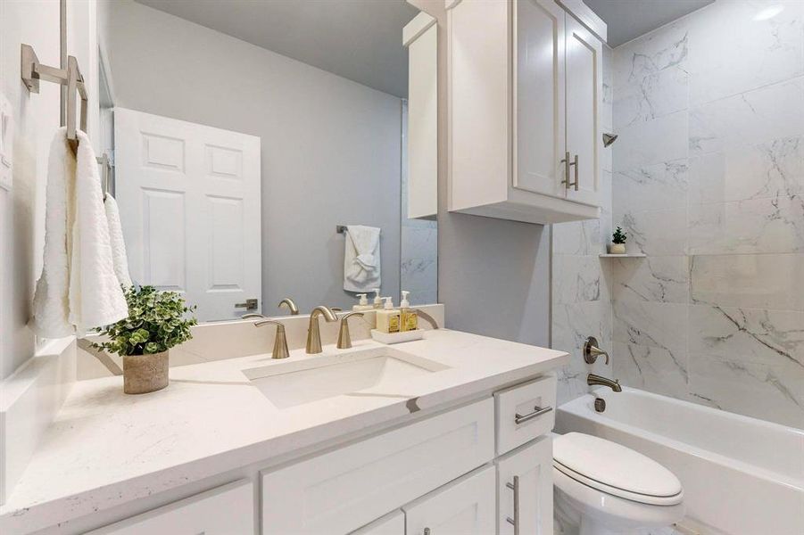 Full bathroom featuring tiled shower / bath combo, vanity, and toilet