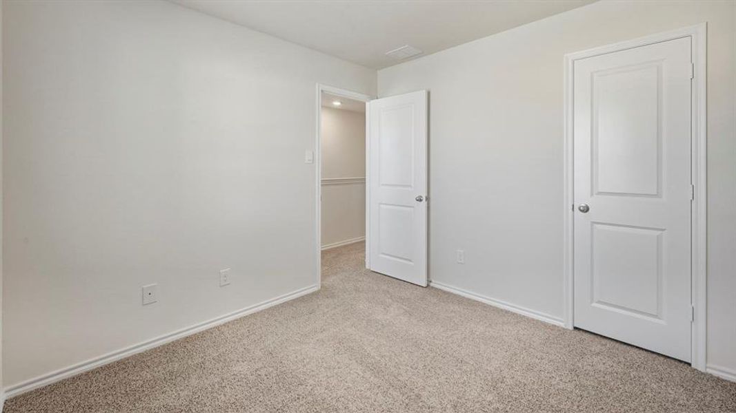 Unfurnished bedroom with light colored carpet and baseboards