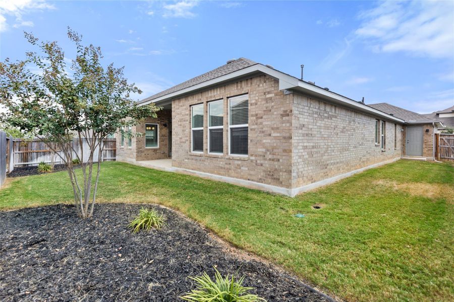 View of home's exterior featuring brick siding, a fenced backyard, a patio, and roof with shingles
