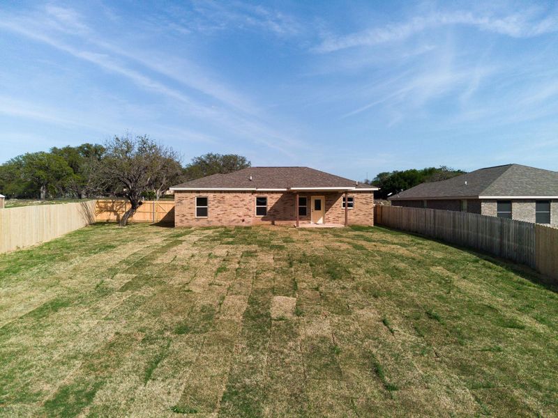 Rear view of house featuring brick siding, a fenced backyard, and a lawn Rear view of house featuring brick siding, a fenced backyard, and a lawn