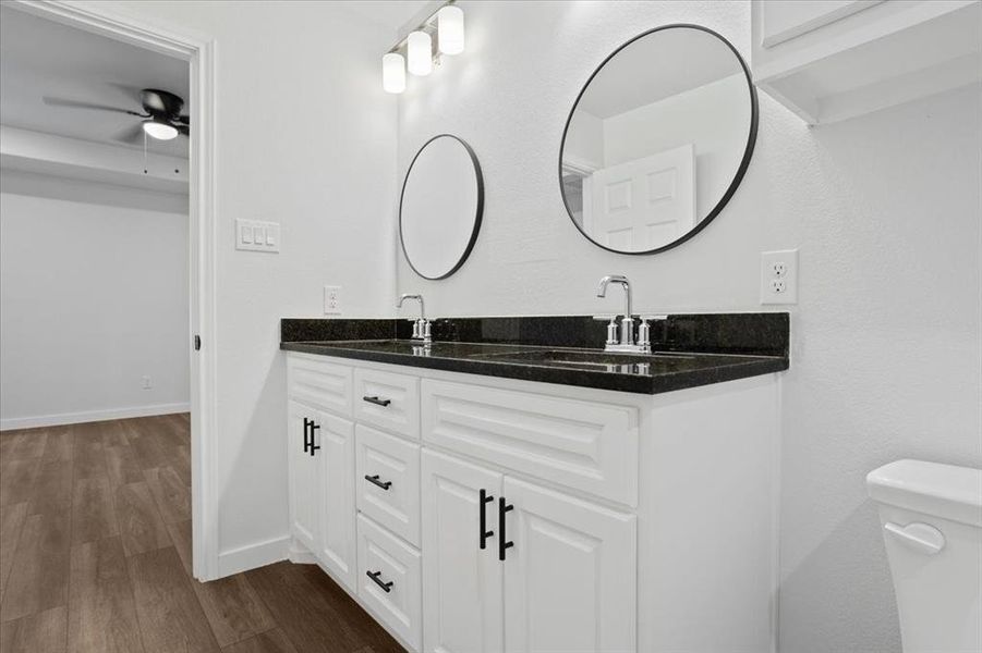 Bathroom featuring ceiling fan, toilet, hardwood / wood-style floors, and double sink vanity