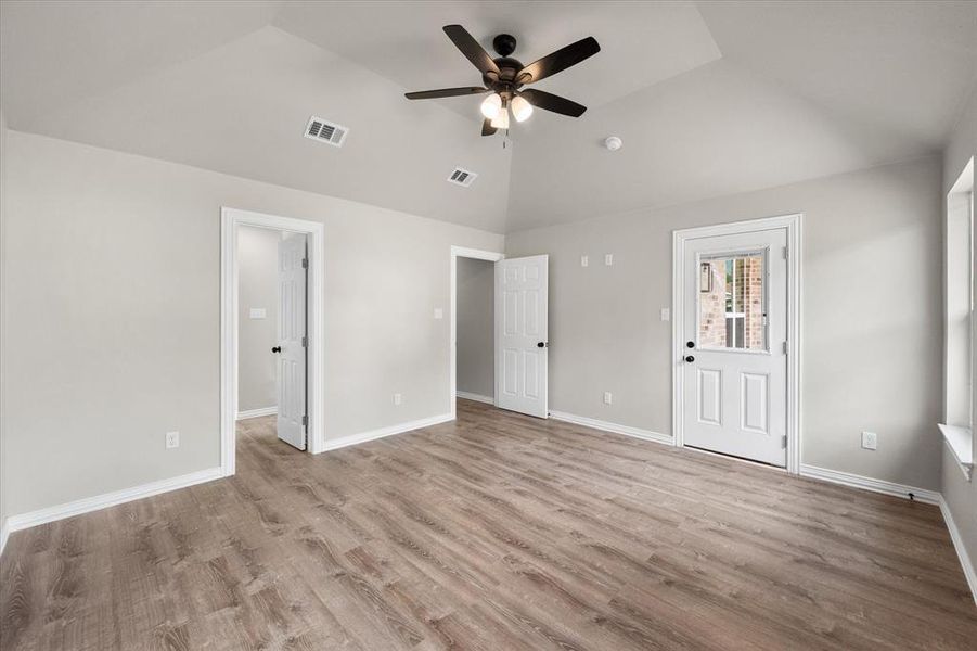 Spacious room with vaulted ceilings and a ceiling fan, featuring wood-finish flooring