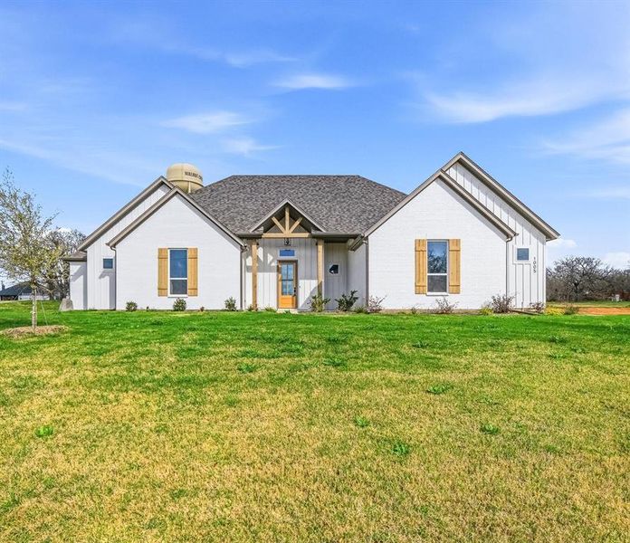 White brick exterior featuring dark shingle roofing and natural wood shutters