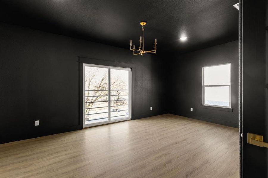 Spare room featuring a textured ceiling, a notable chandelier, and wood finished floors