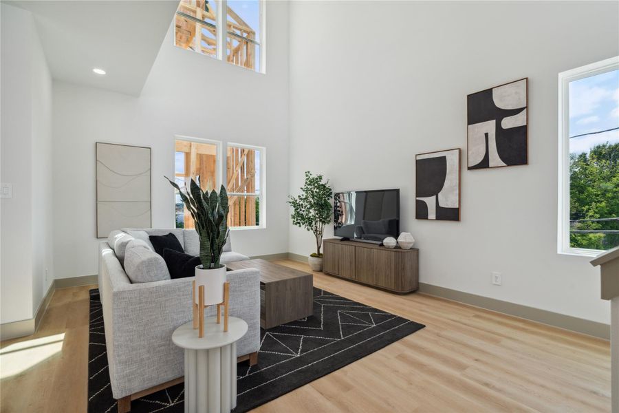 Soaring ceilings and walls of natural light create an atmosphere of airy elegance in this open-concept living space.