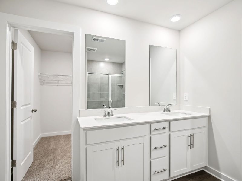 The primary bathroom offers dual vanity sinks and a walk-in shower.