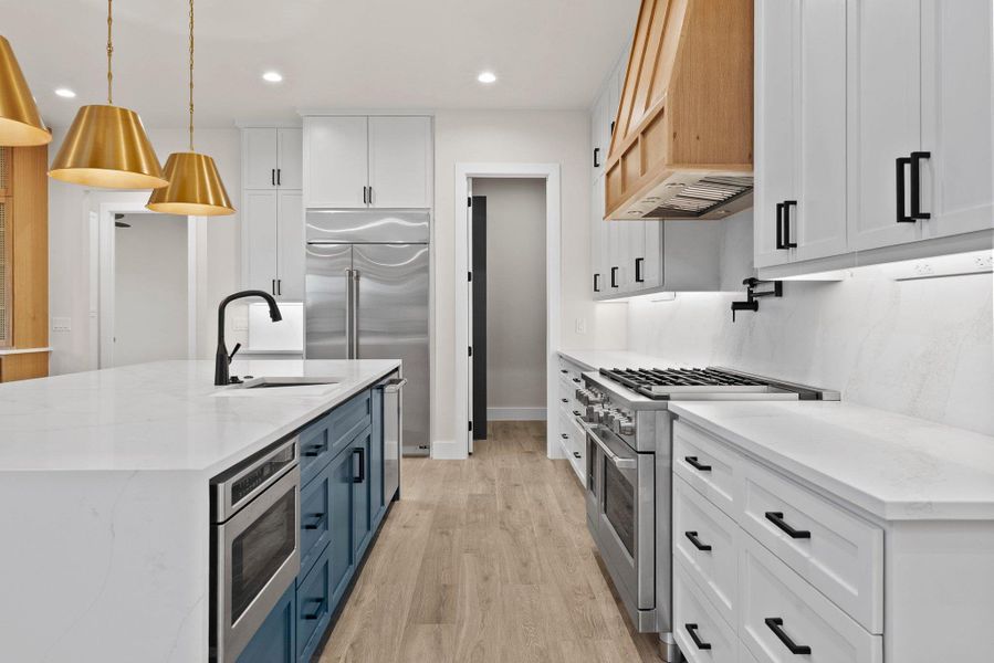 A well-lit culinary space showcases an expansive island with a sink and modern appliances.