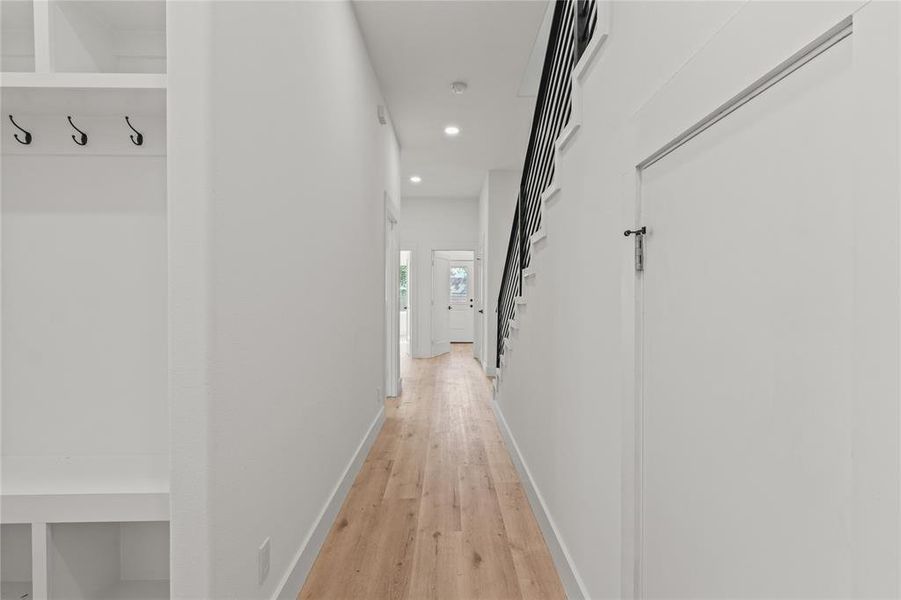Hallway featuring light wood finished floors, recessed lighting, and stairs