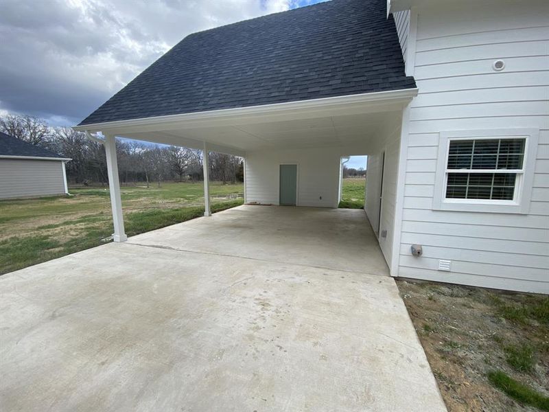 View of car parking featuring a yard and a carport