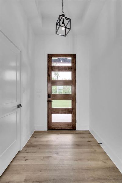 Foyer entrance with light hardwood / wood-style flooring and an inviting chandelier