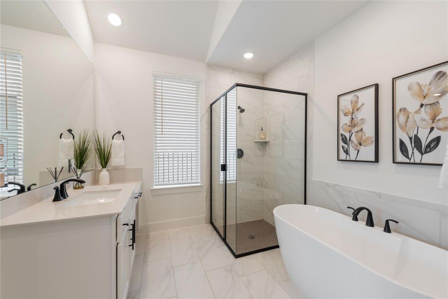 A modern primary bathroom features a spacious walk-in shower and a freestanding soaking tub. A modern primary bathroom features a spacious walk-in shower and a freestanding soaking tub.
