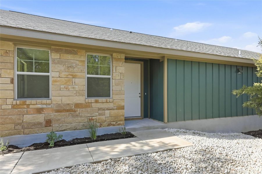 View of exterior entry with stone siding and board and batten siding