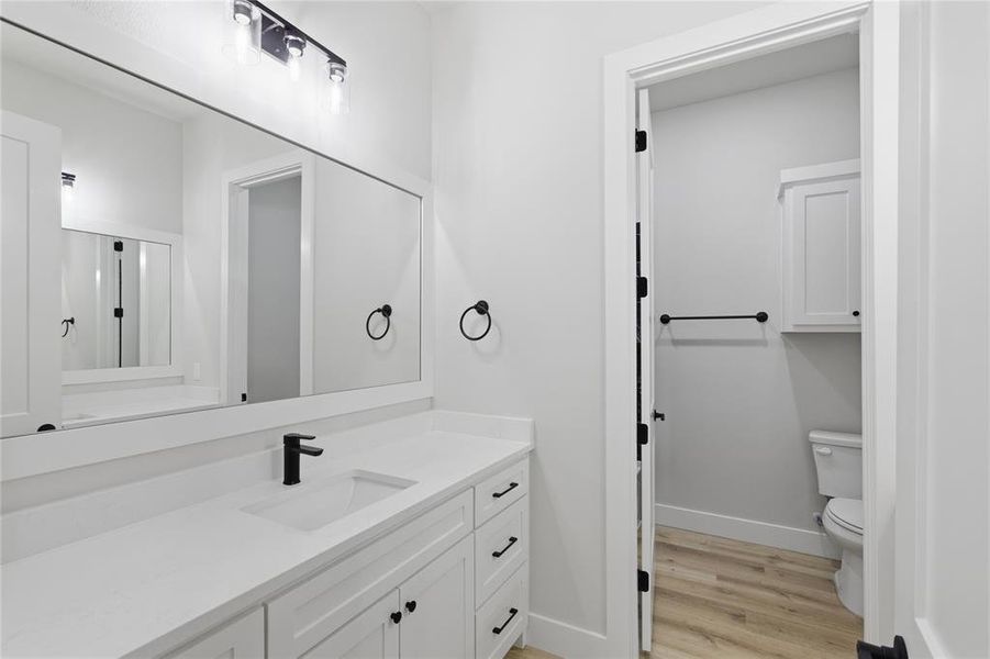 Bathroom vanity featuring a white countertop with an integrated rectangular sink and a matte black faucet