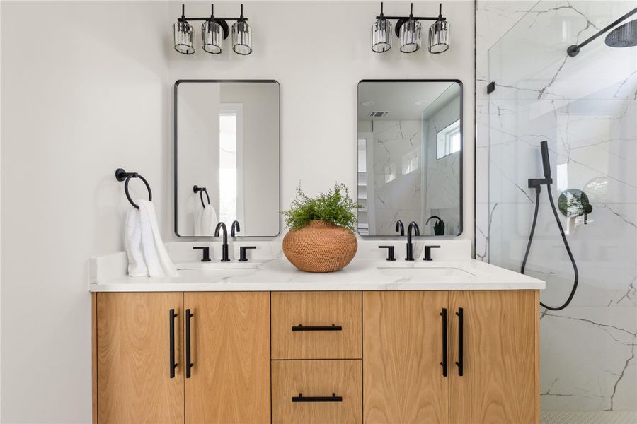 Clean lines and stone counters define this modern bathroom vanity area alongside a glass-enclosed shower.