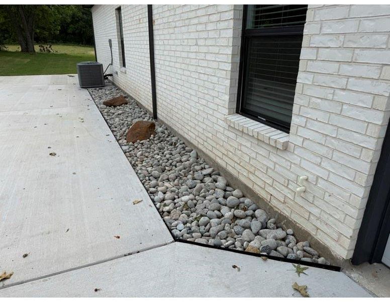 White brick exterior with a black-framed window and a concrete patio