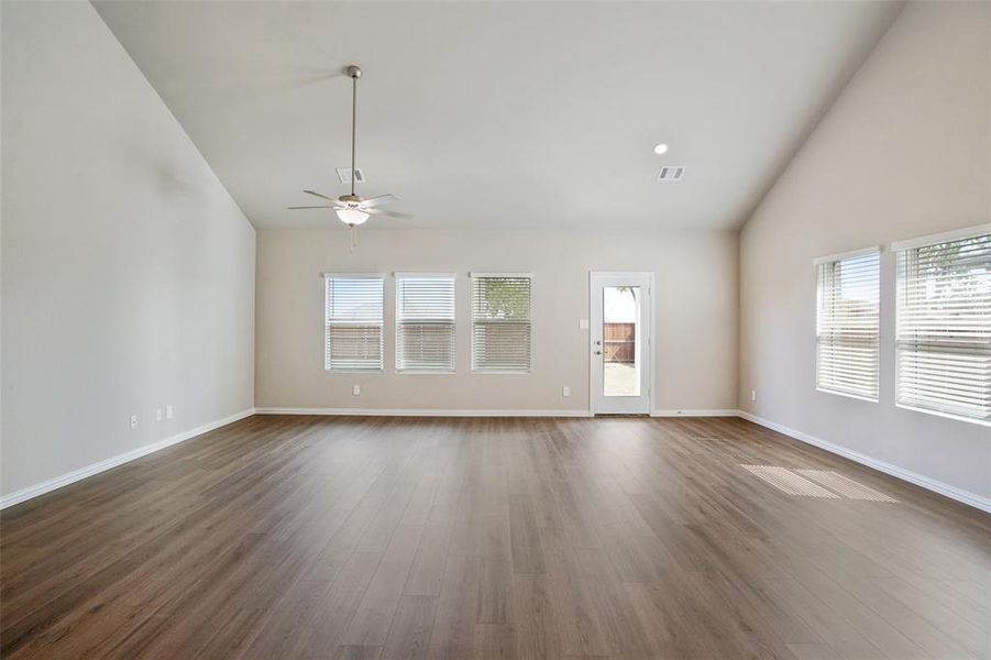 Unfurnished living room featuring hardwood / wood-style flooring, high vaulted ceiling, and ceiling fan