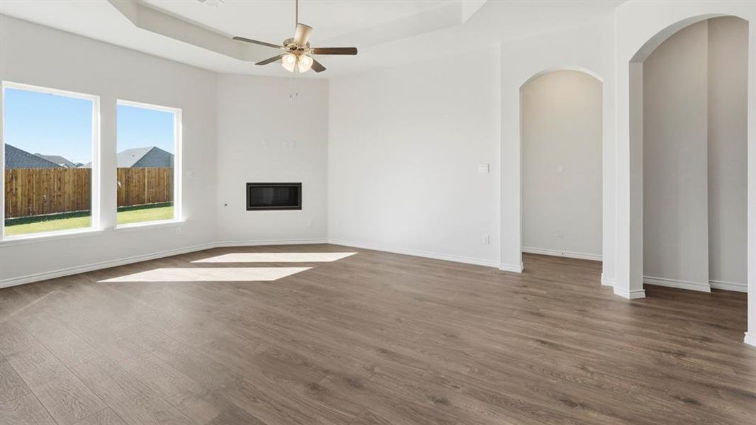 Spacious living area featuring light wood-look flooring, a modern fireplace, and a ceiling fan Spacious living area featuring light wood-look flooring, a modern fireplace, and a ceiling fan