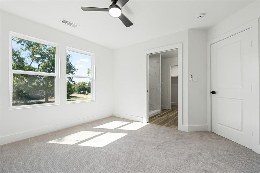 Unfurnished bedroom featuring light colored carpet, ceiling fan, and ensuite bath