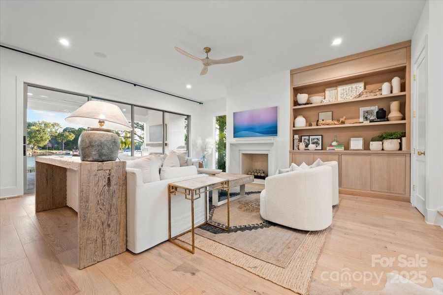 Open concept floorplan and Great Room with waterfront views, custom built fireplace with designer cast stone surround, stacked sliding glass doors opening to the covered patio, and built in media wall w/ integrated sound system. Open concept floorplan and Great Room with waterfront views, custom built fireplace with designer cast stone surround, stacked sliding glass doors opening to the covered patio, and built in media wall w/ integrated sound system.