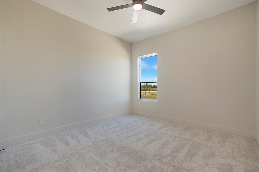 Carpeted spare room featuring baseboards and ceiling fan Carpeted spare room featuring baseboards and ceiling fan