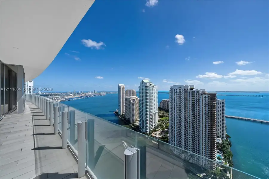 Expansive wrap-around balcony featuring large-format tile flooring and frameless glass railings Expansive wrap-around balcony featuring large-format tile flooring and frameless glass railings