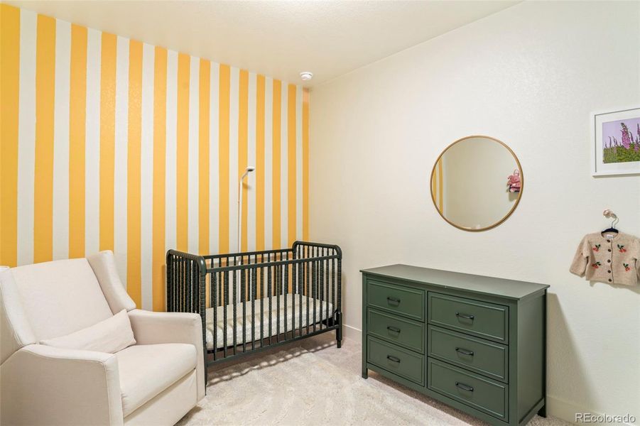 Light-filled bedroom with soft finishes, perfect as a nursery or guest room in this thoughtfully designed home in the Three Hills community