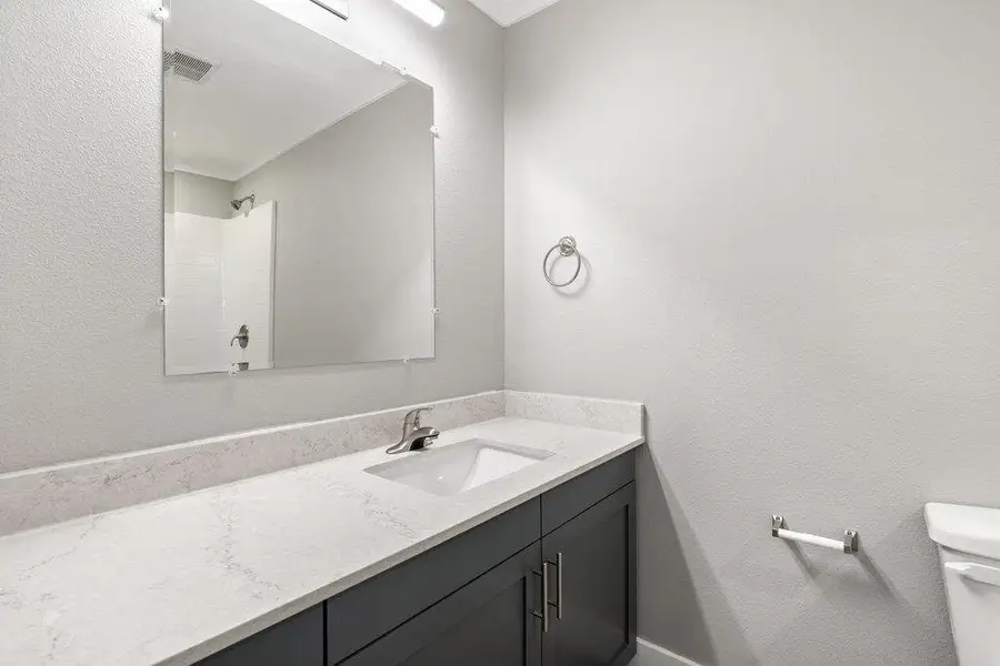 Secondary bedroom upstairs features quartz countertops, and shower/tub combo