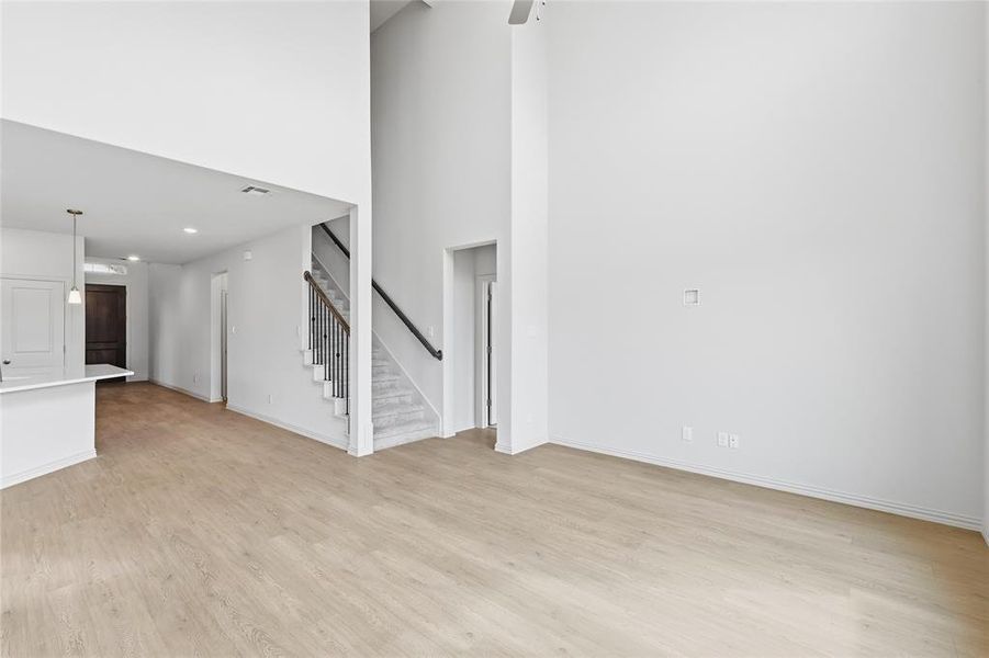 Unfurnished living room with light wood-type flooring, a high ceiling, and recessed lighting