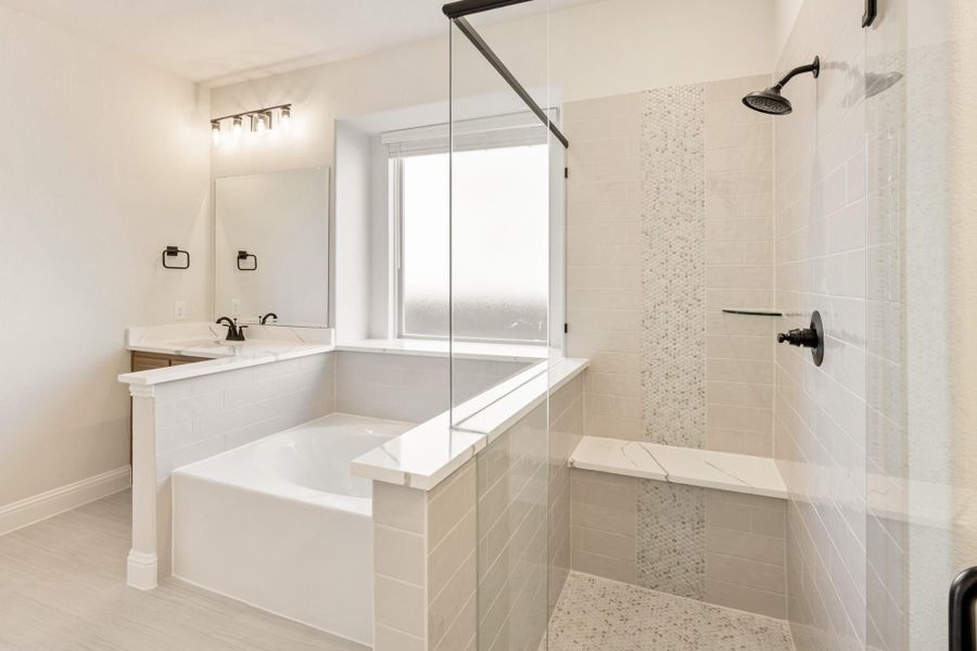 Master bathroom with soaking tub, glass walk-in shower, tile walls, and single vanity with black fixtures Master bathroom with soaking tub, glass walk-in shower, tile walls, and single vanity with black fixtures