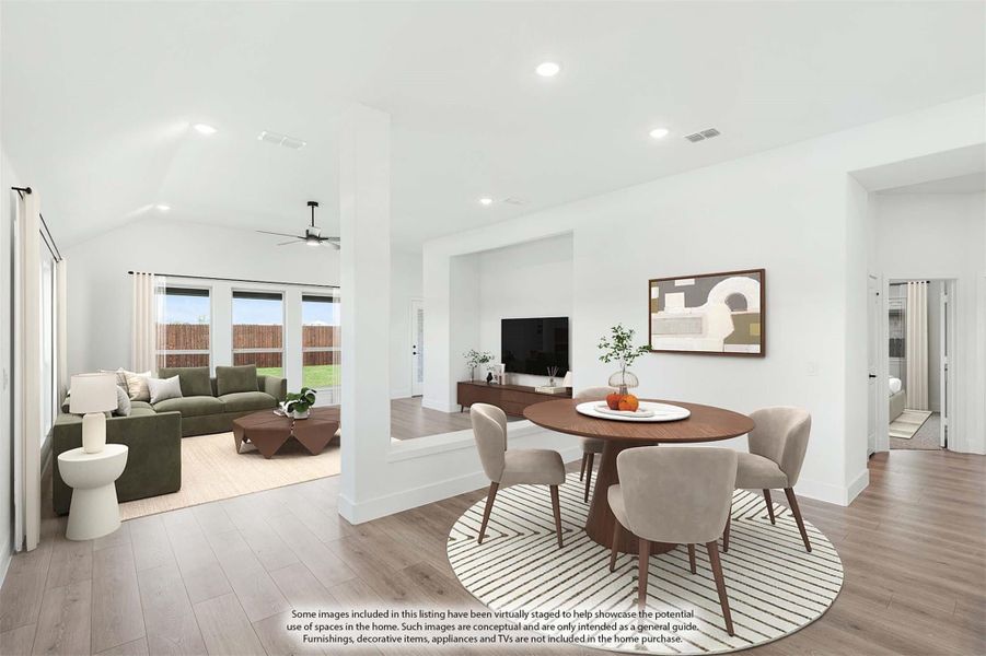 Open-concept dining and living area with hardwood floors, round dining table, and vaulted ceiling