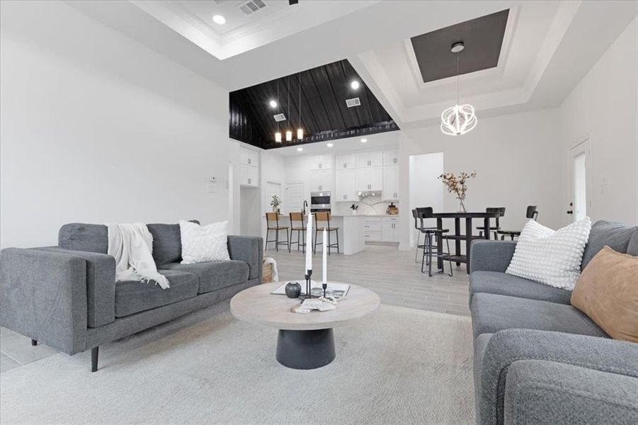 Living area featuring light wood-style floors, recessed lighting, a raised ceiling, and a towering ceiling