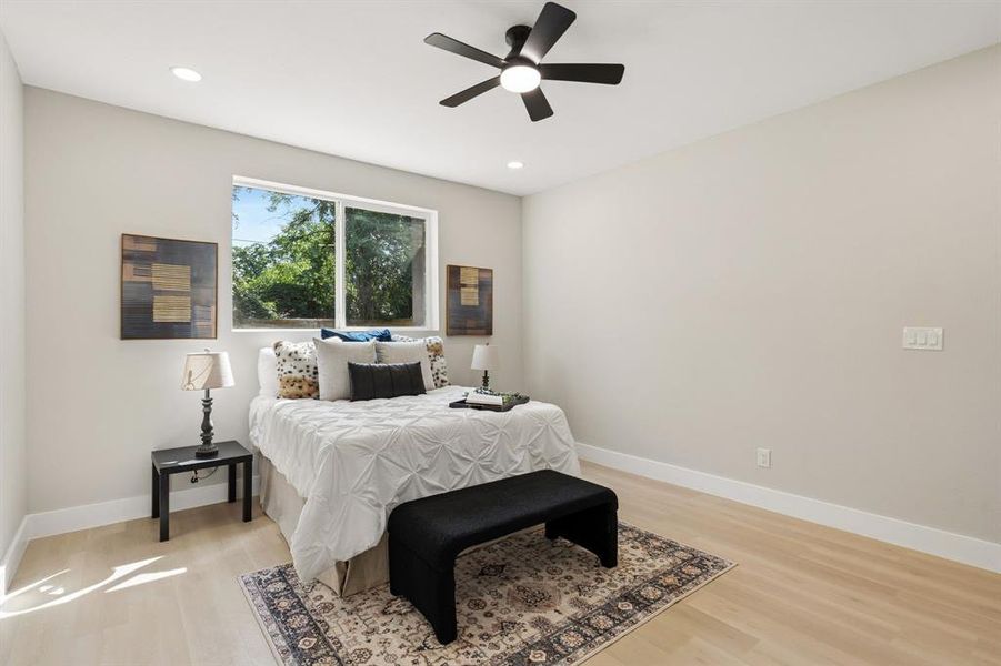 Spacious room featuring wood-finish flooring, a large window, a ceiling fan, and recessed lighting Spacious room featuring wood-finish flooring, a large window, a ceiling fan, and recessed lighting