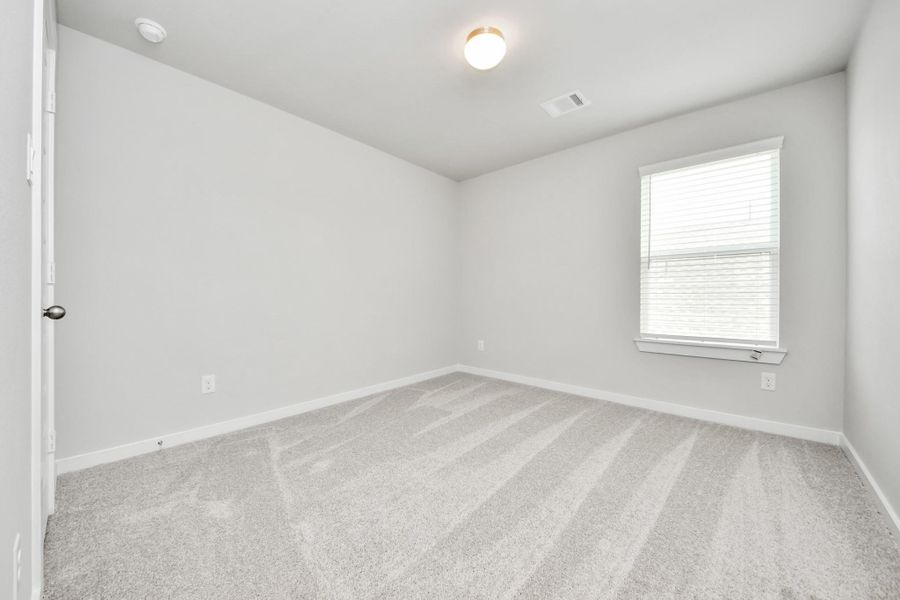 Secondary bedroom features plush carpeting, large windows that let in plenty of natural light, bright paint, and spacious closets. Sample photo of completed home with similar floor plan. Actual colors and selections may vary.