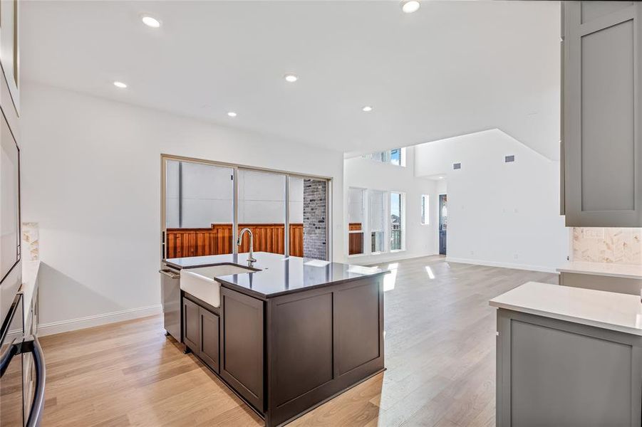 Kitchen featuring gray cabinetry, sink, a center island with sink, and light hardwood / wood-style flooring