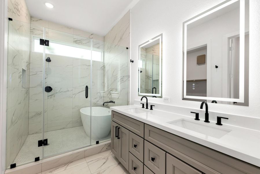 Indulge in spa-like luxury with this breathtaking primary bathroom, featuring an elegant double vanity with sleek quartz countertops, modern black fixtures, and illuminated mirrors. The stunning wet room design showcases a freestanding soaking tub and an oversized glass-enclosed shower adorned with marble-inspired tile. Indulge in spa-like luxury with this breathtaking primary bathroom, featuring an elegant double vanity with sleek quartz countertops, modern black fixtures, and illuminated mirrors. The stunning wet room design showcases a freestanding soaking tub and an oversized glass-enclosed shower adorned with marble-inspired tile.