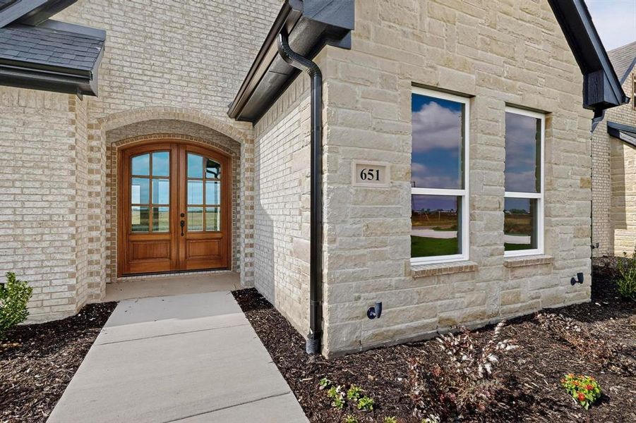 Property entrance featuring stone siding, french doors, and brick siding Property entrance featuring stone siding, french doors, and brick siding