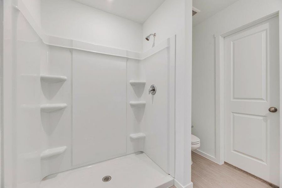 Full bathroom featuring a stall shower and light wood-type flooring